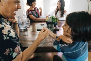 dad and son are playing thumb wars at the breakfast table.
