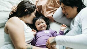 Baby newborn snuggling in bed with mom and dad.