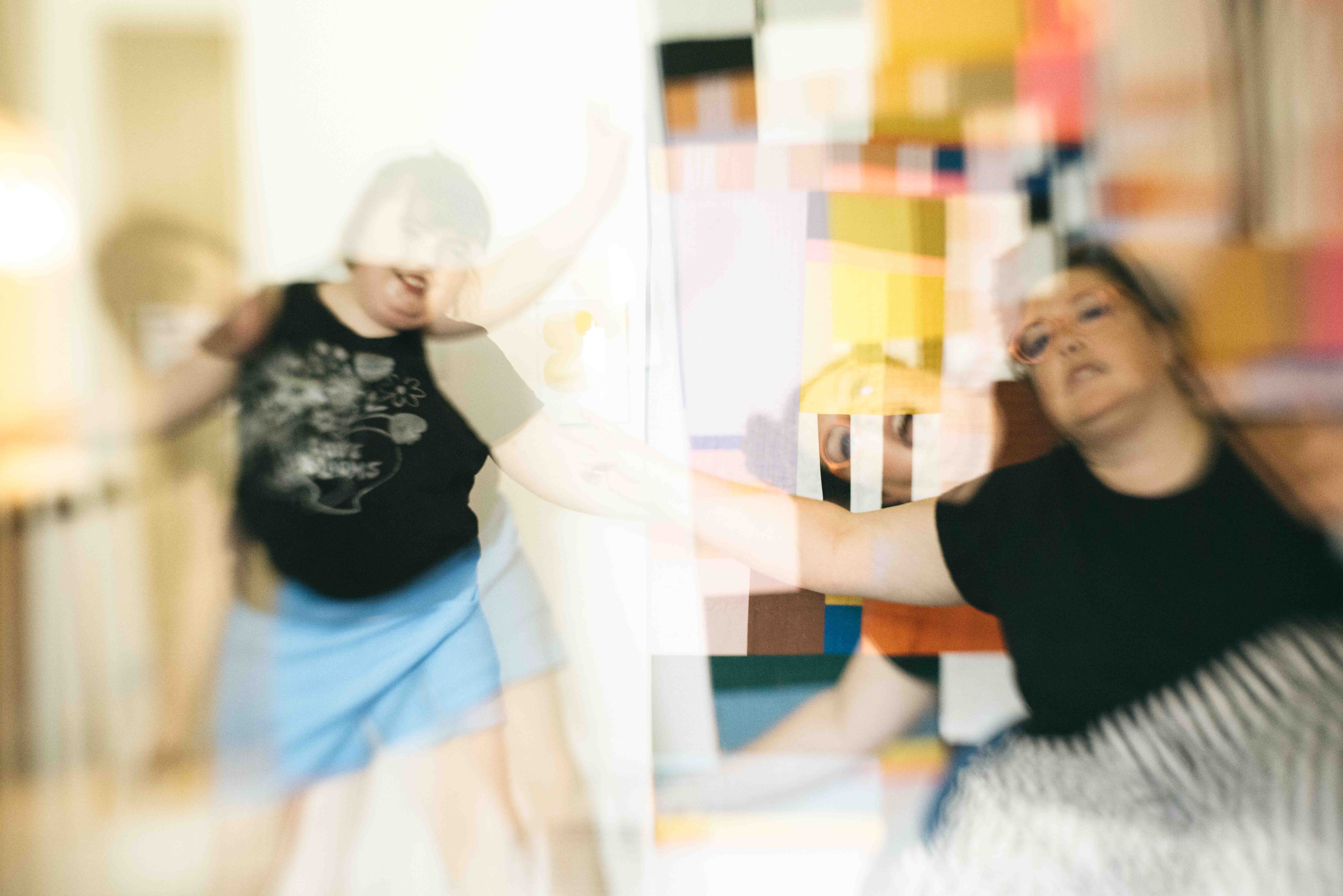 Mom and teen daughter are dancing in the living room.