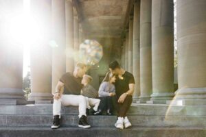 Family is kissing each other as they sit on the stone steps on the stage at the Music Concourse during a photo session.