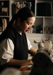 PATO owner is sewing at her sewing machine in her San Francisco studio.