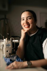 Artist is smiling at her sewing machine.