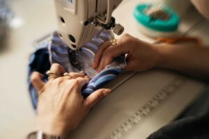 Woman is feeding fabric through her sewing machine.