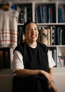 Artist is laughing in her studio with vintage fabric in the background.