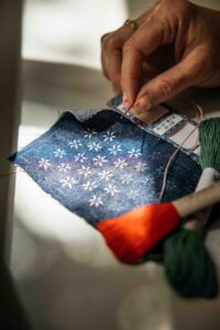 Woman holding needle as she does shashiko embroidery in her San Francisco studio.