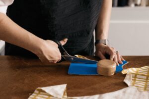 Woman is cutting fabric with scissors on her cutting table.