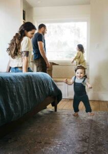 Mom and dad are playing with their toddler kids in the bedroom.