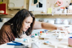 Ceramic artist moves clay objects on her studio table during a creative branding session.
