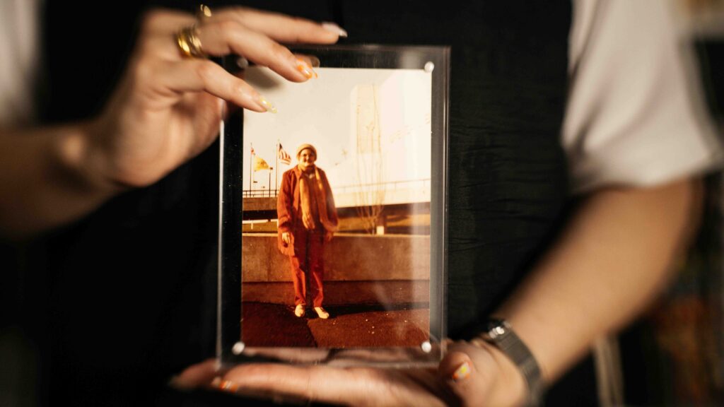Textile artist holding a picture frame of her grandmother.