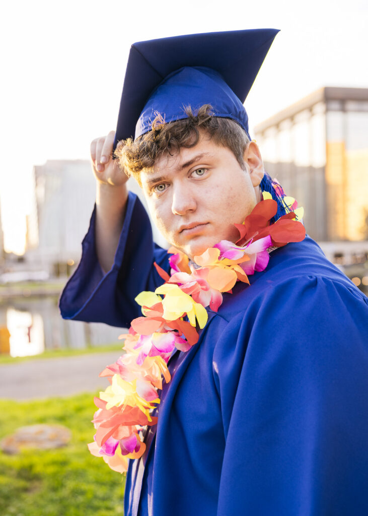 High school senior tipping his graduation cap at Lake Merritt at sunset during his senior photo session.