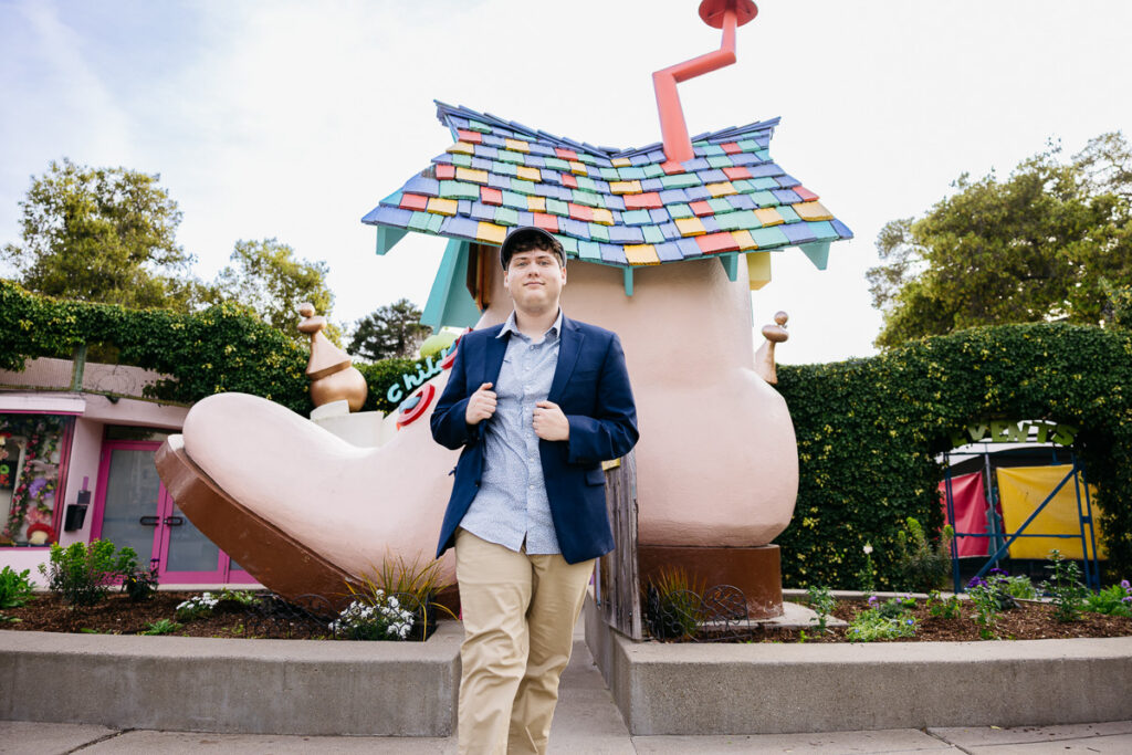 High school senior is proudly walking in front of the Fairyland gates during his family photo session.
