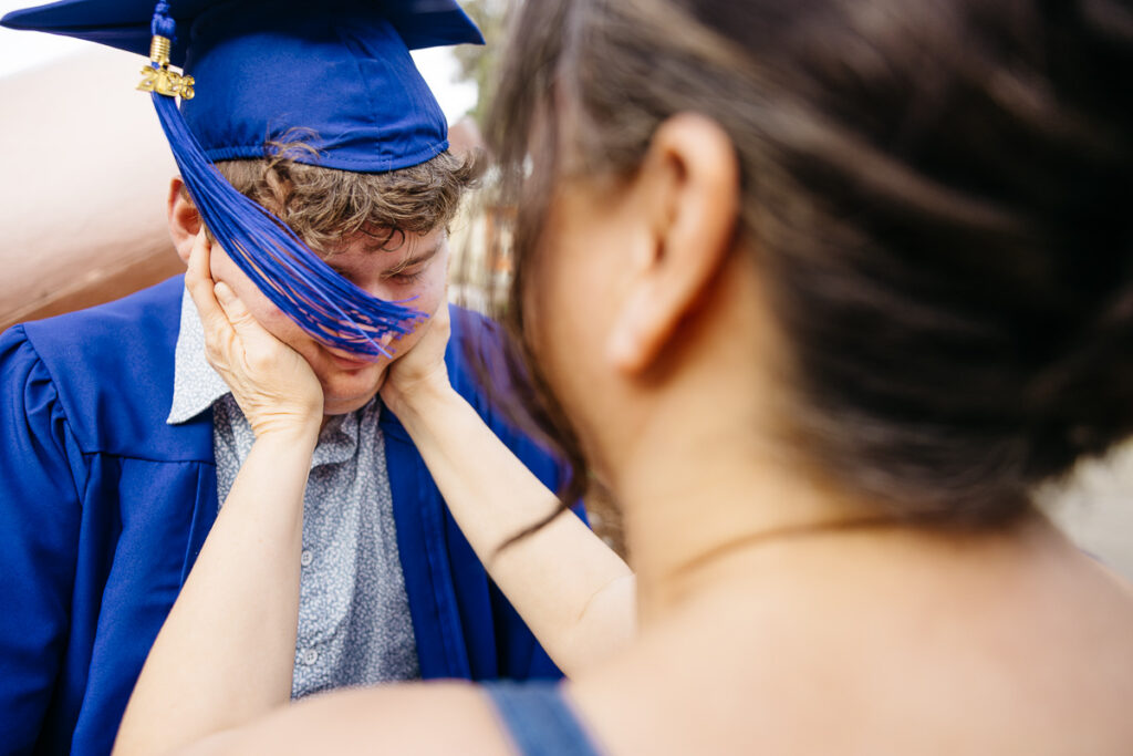 Mom is holding the cheeks of her high school graduate during a family photo session.