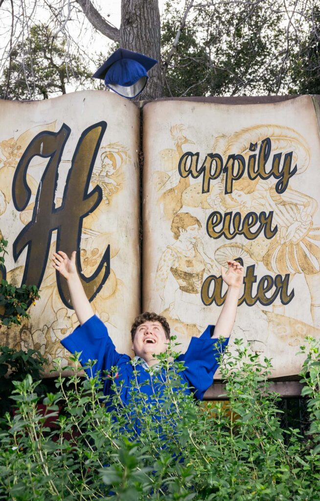 Senior graduate throws his cap at the Fairyland gates during his family photo session.