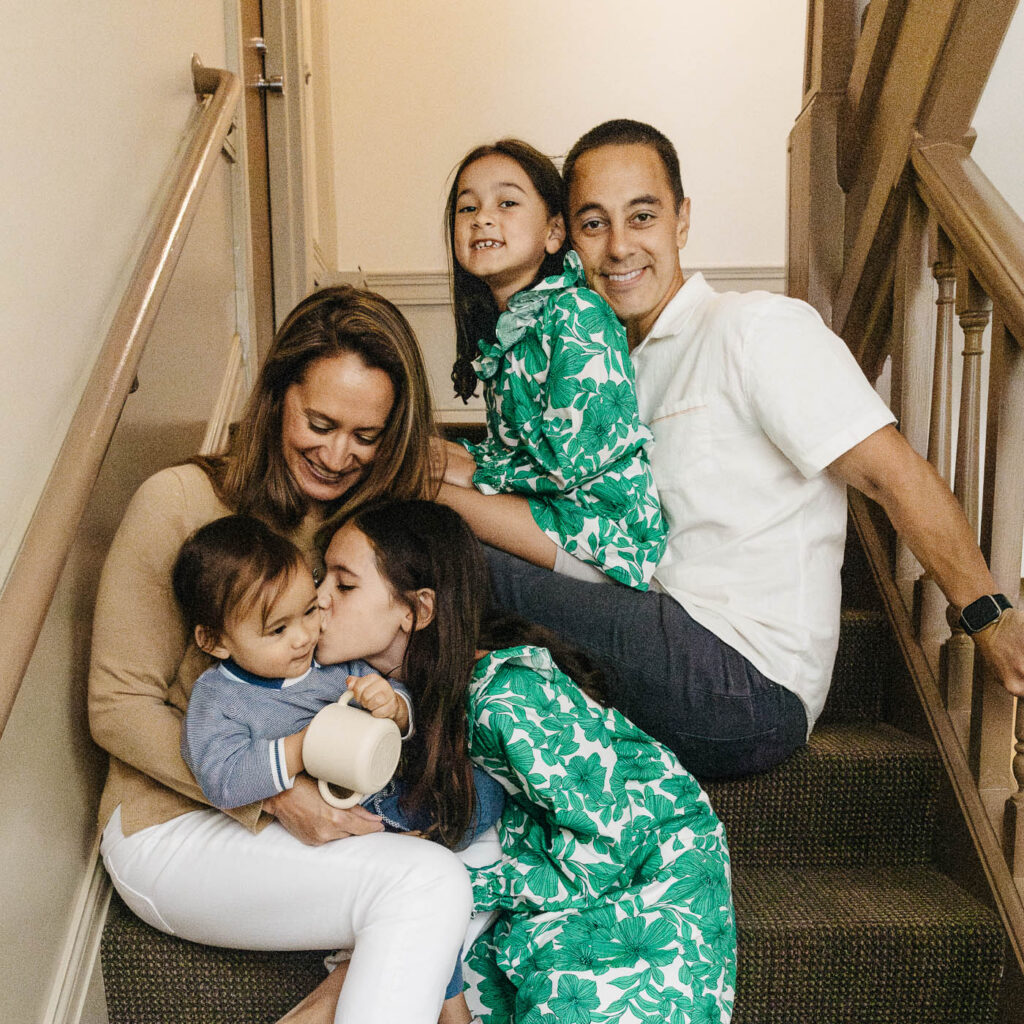 Family is sitting on the stairwell of their home for a goodbye photo to their home