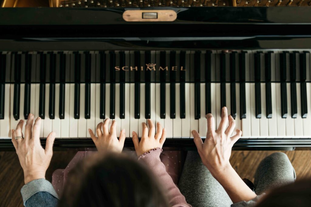 Mom and daughter are playing at the piano during a family photo session with Carmen Dunham.
