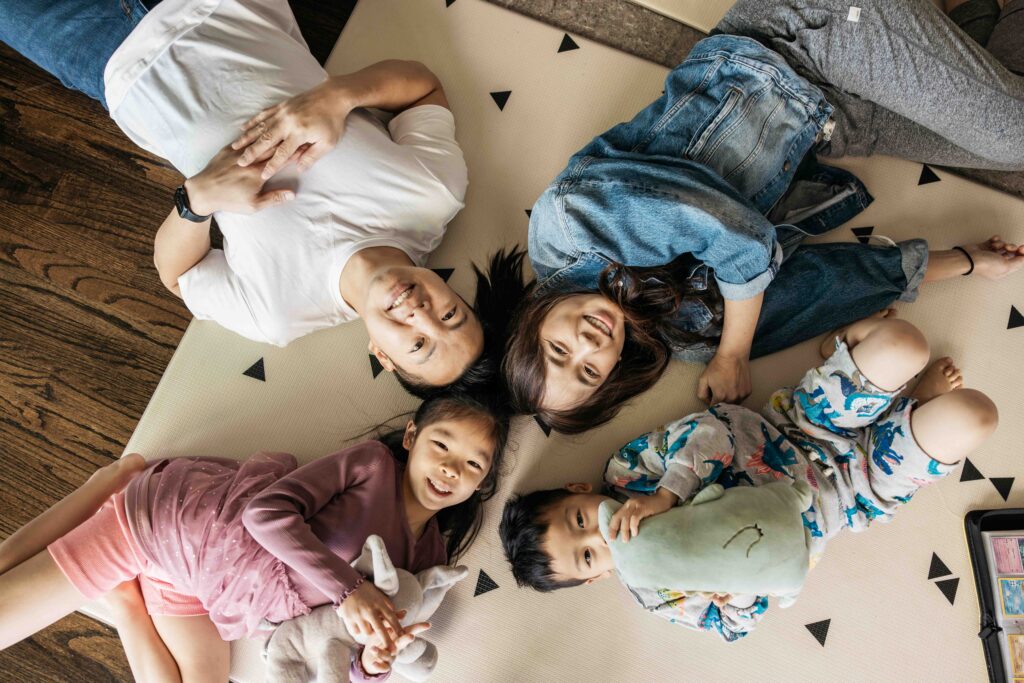 Mom, dad, and sibling brother and sister are laying on the ground smiling during a family photo session.