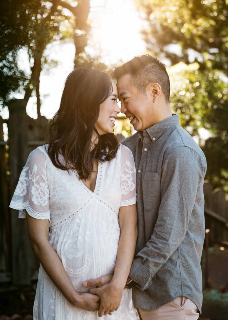 Young expecting parents are smiling at each other with anticipation during a maternity session at home.