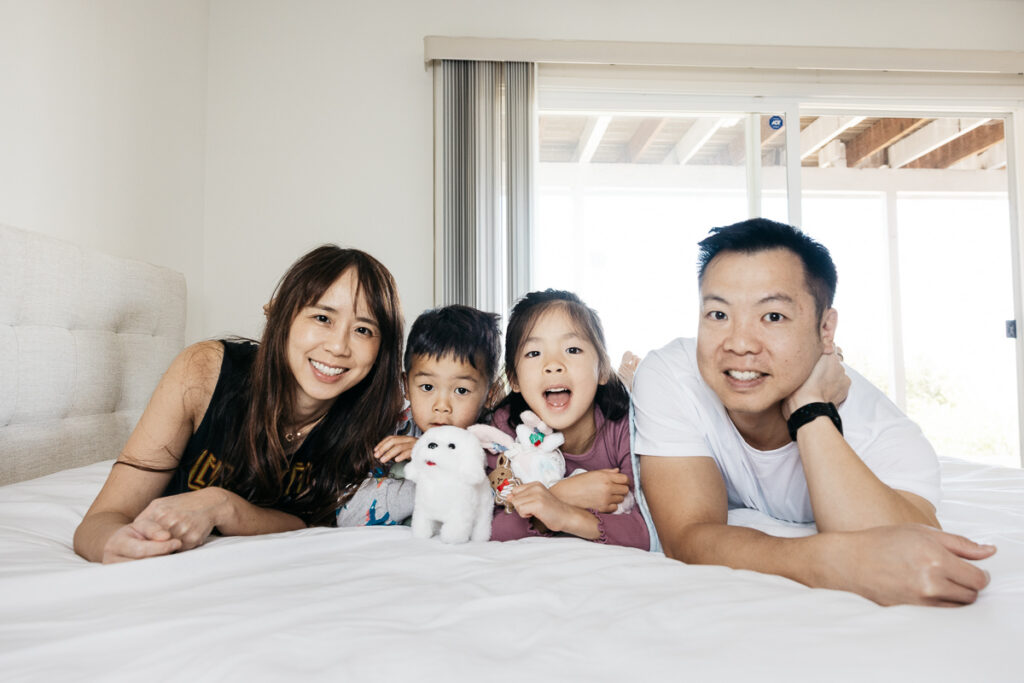 Family is cuddling on the bed with stuffed animals during a family photo session.