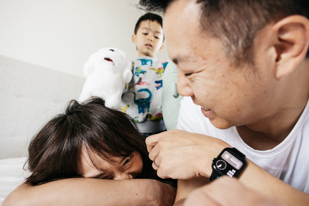 Mom is having a case of the giggles on the bed with family during a family photo session.