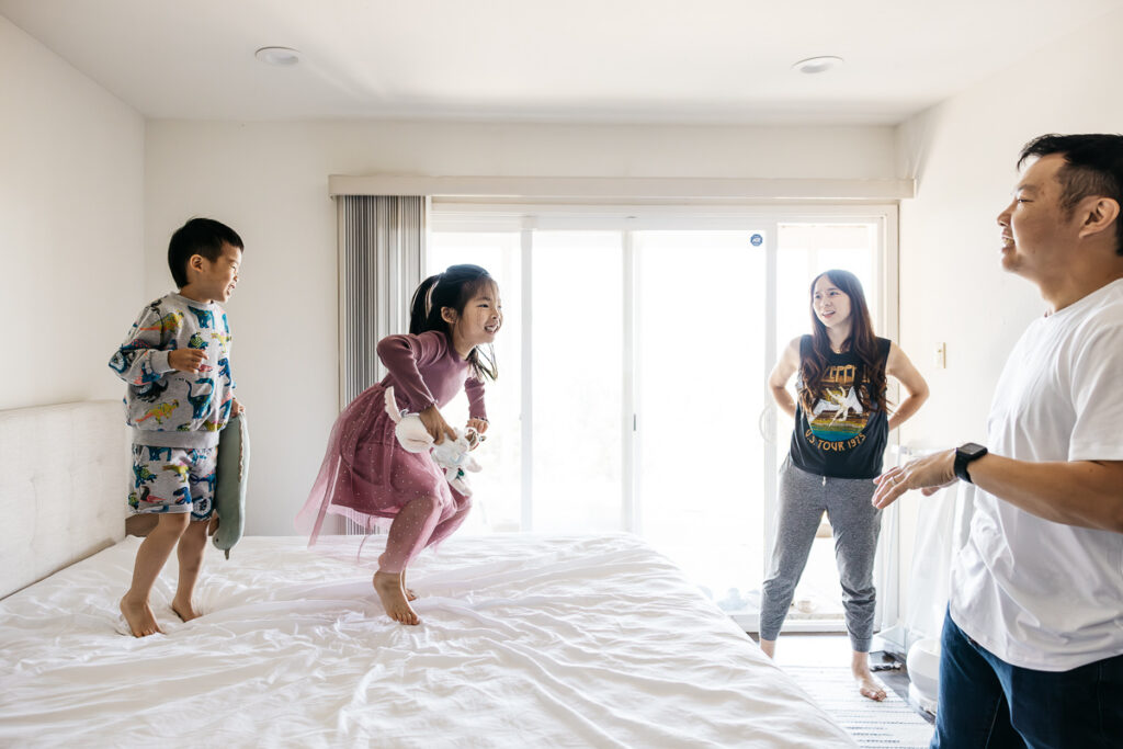 Young sibling brother and sister are jumping on the bed.