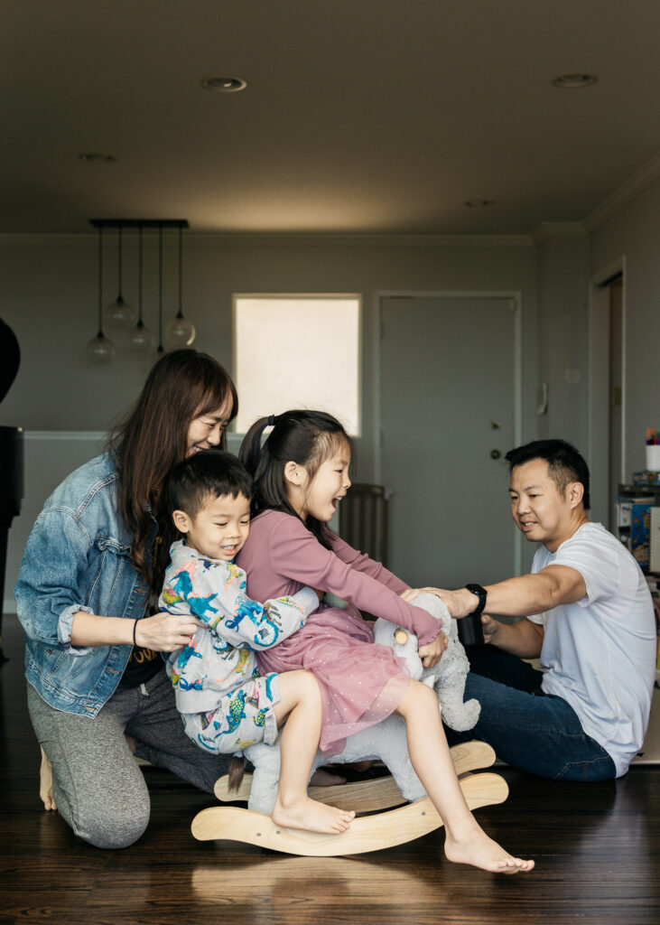 Mom and dad are rocking the kids in the living room during a family photo session.