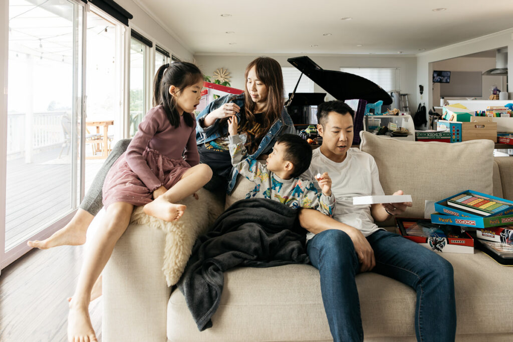 Family is laying on the sofa while they look at different board games.