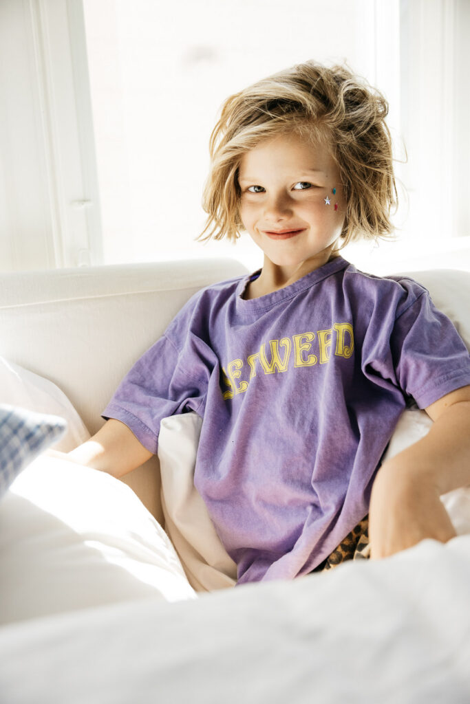 Older brother is smiling with mischief on the bed.